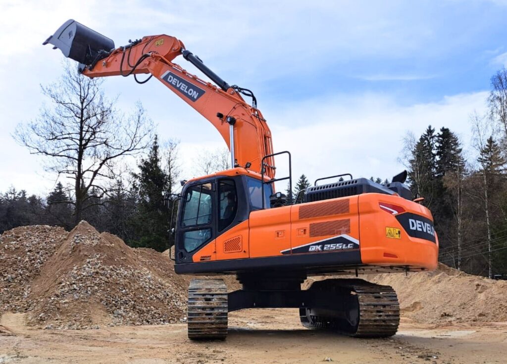 koparka gąsienicowa develon w kolorze pomarańczowym na placu budowy